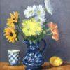 Bright flowers in a blue pitcher on wooden chest