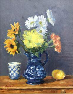 Bright flowers in a blue pitcher on wooden chest